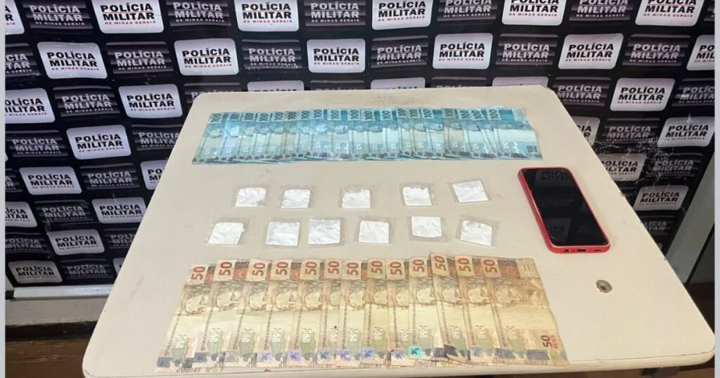 Material apreendido durante operação policial em Espinosa após prisão por tráfico de drogas: valores em espécie, substâncias entorpecentes e aparelho celular apresentados pela Polícia Militar.