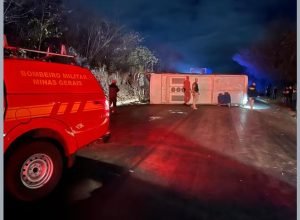 Micro-ônibus tombado na BR-251 em Montes Claros após escorregar em pista molhada; equipes do Corpo de Bombeiros e Samu prestam socorro.
