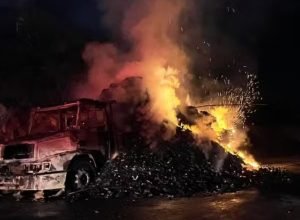 Caminhão em chamas na BR-251, em Montes Claros, com fumaça intensa enquanto equipes tentam controlar o incêndio na rodovia.