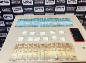 Material apreendido durante operação policial em Espinosa após prisão por tráfico de drogas: valores em espécie, substâncias entorpecentes e aparelho celular apresentados pela Polícia Militar.